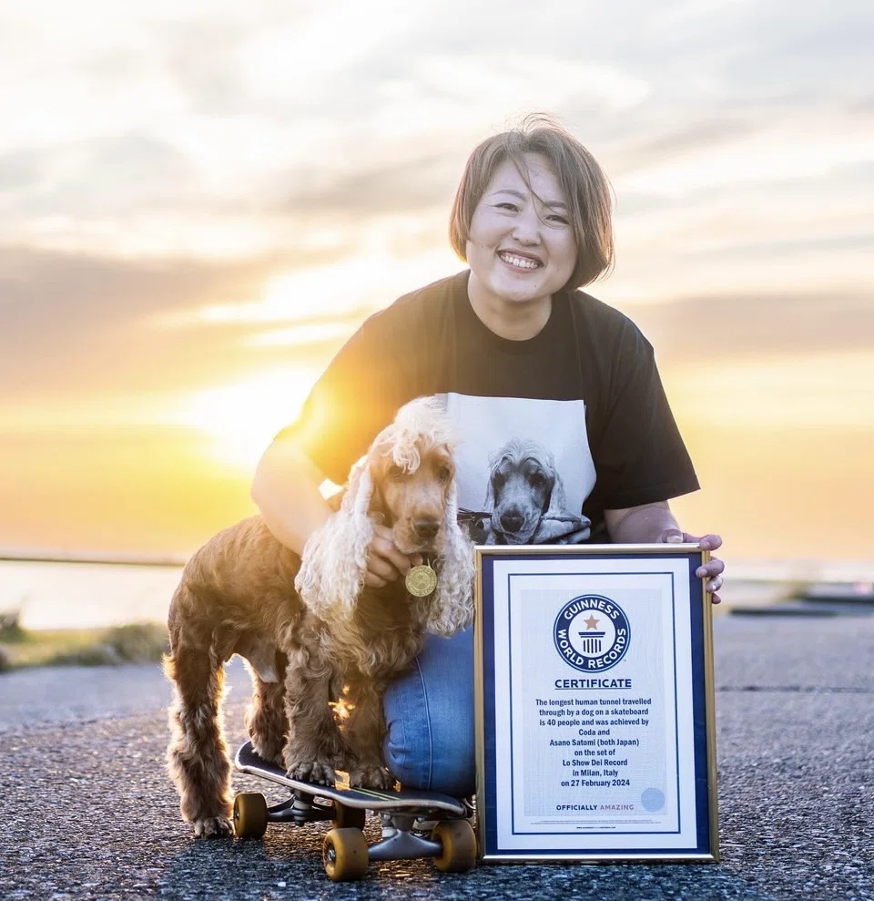 ギネス世界記録を達成した浅野里実さんとスケートボード犬のコーダくん、認定証とメダルを持って記念撮影